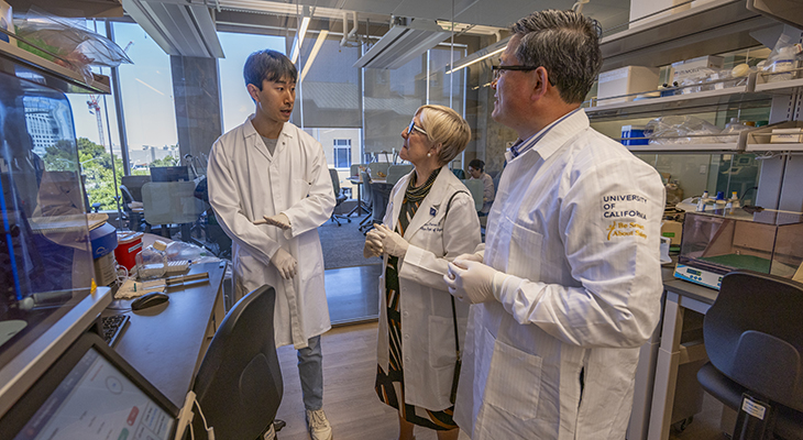 Dr. Aijun Wang, Dr. Diana Farmer and a graduate student are wearing white lab coats.
