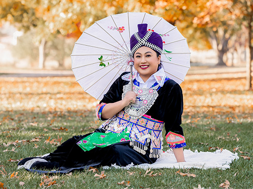 Portrait of a smiling woman with dark, long hair, wearing white shirt with black dots
