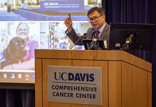 A middle-aged man in a suit speaking at a podium in front of an audience.