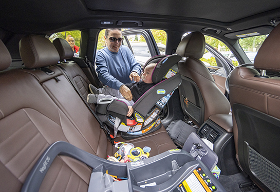 Woman checks on child in car seat in back seat