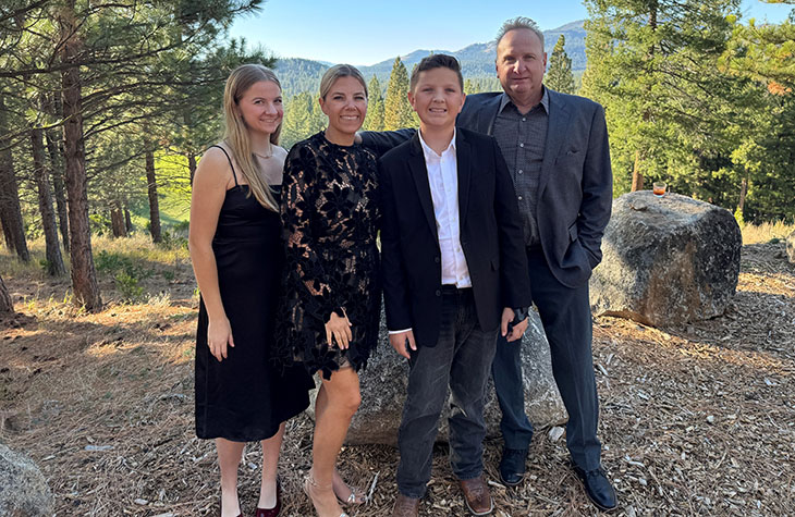A family of four - two adults, two children, poses outside for a portrait