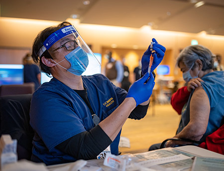 A health care worker prepares a vaccine for a patient.