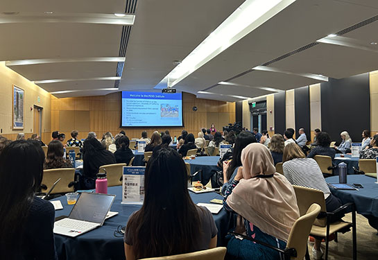 A large group of people are gathered to watch a presentation at the UC Davis MIND Institute auditorium