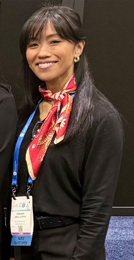 Student wearing ID badge and red scarf stands posing for photo