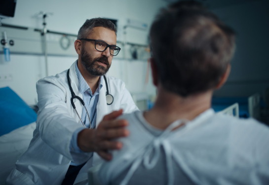 Doctor leaning forward with hand on patient's shoulder.