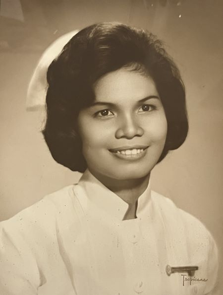 A black and white portrait of a smiling woman in a nurse&rsquo;s uniform. 