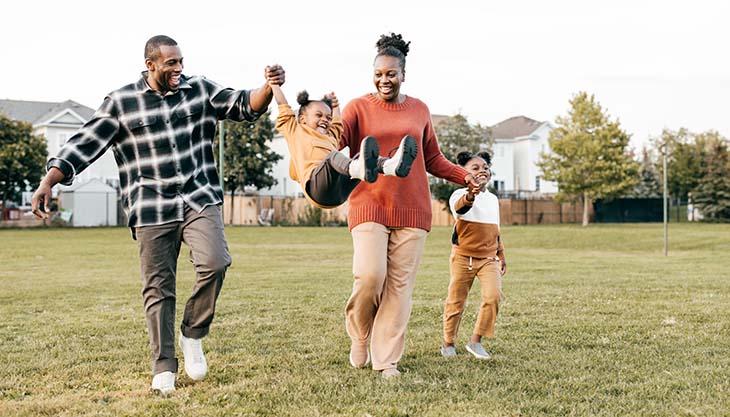 A mom, dad and two children play together outside.