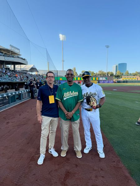 Three men standing on grassy field.