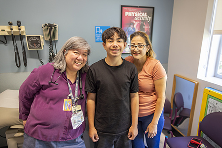 Hispanic teen with mom and female Asian doctor.