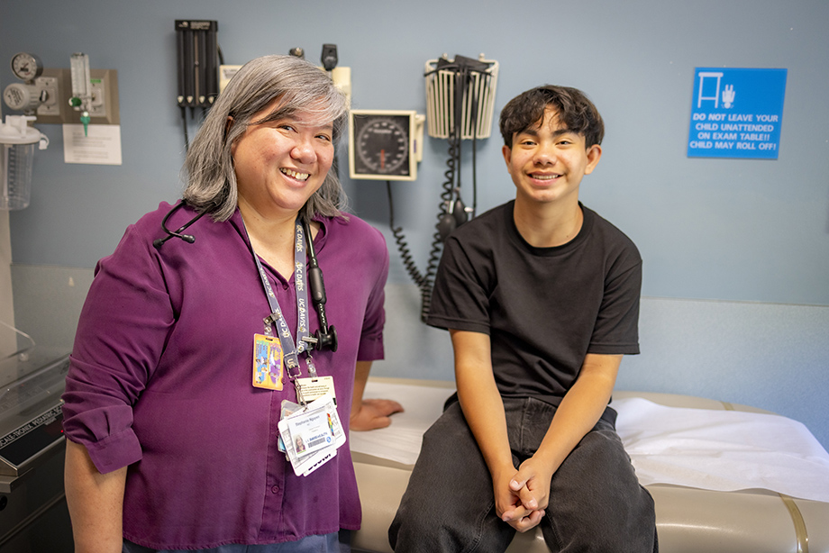 Hispanic teen posing for a pic with his Asian female doctor.