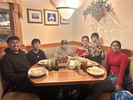 Woman and five kids sit at a table in a restaurant.