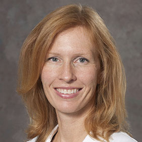 Portrait of red-headed woman in white coat smiling 