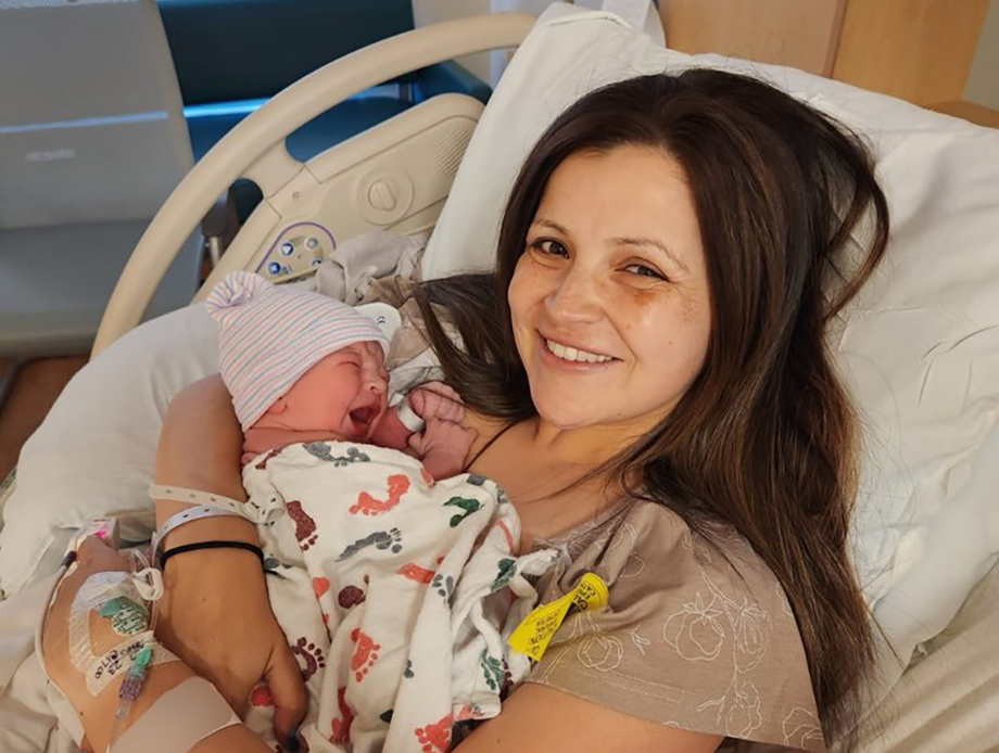 Woman in hospital bed holding newborn