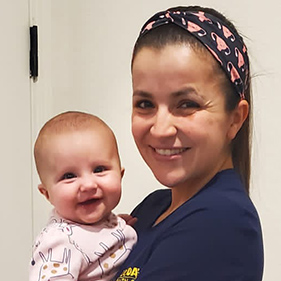 Woman in blue scrubs holding baby girl.