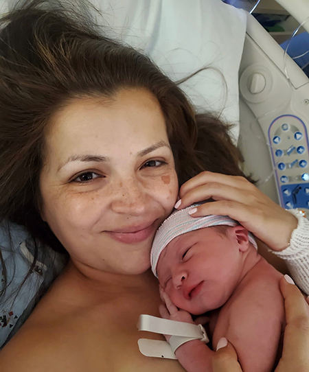 Woman in hospital bed holding newborn.