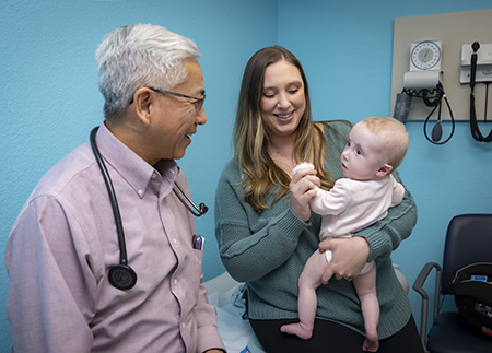 Woman holds baby with doctor