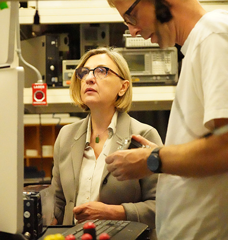 Professor Laura Marcu with a short blond hair looking up. Next to her is Julien Bec who is looking at small object he is holding in his hands.