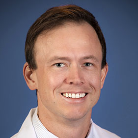 a physician with brown hair wearing a white medical coat