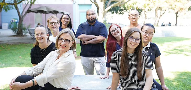 An outdoor picture of nine individuals, including Dr. Laura Marcu, looking straight to the camera.