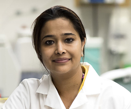 Dr. Bhatnagar wearing a white lab coat and looking at the camera