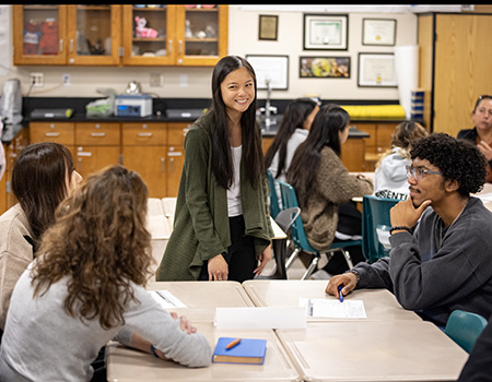 Woman at front of classroom in front of students.