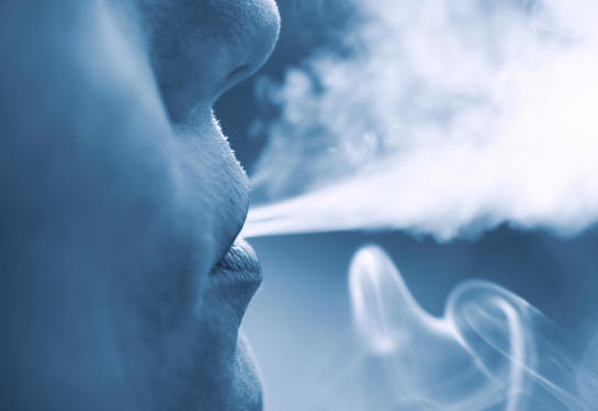 Close-up of a woman's face exhaling smoke