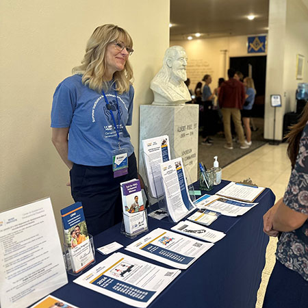 Woman standing at a conference talking to people.