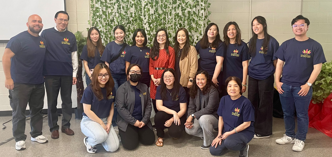 Team members wearing blue shirts stand side-by-side in two rows, posing for a photo