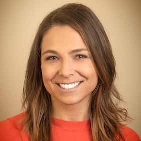 A headshot of a smiling woman wearing an orange sweater.